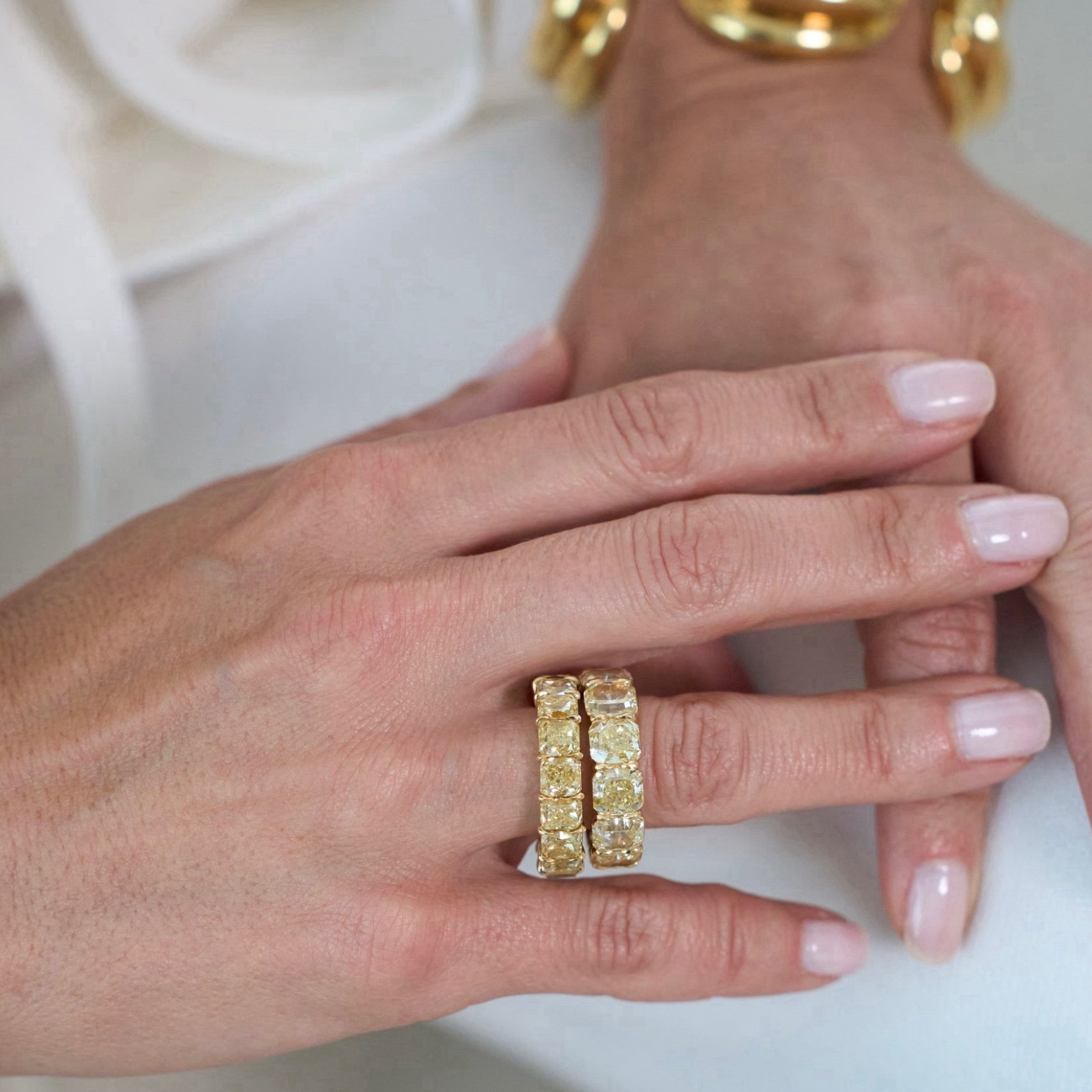 Close-up of a hand wearing two gold rings with a plain background